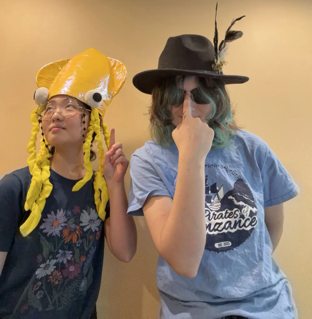 Two club members posing in costume hats